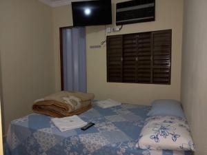 a bedroom with a bed with a blanket and a window at Pousada Catarina in Maringá