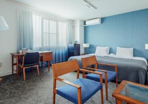 a hotel room with a bed and chairs and a desk at Hotel Graphy Nezu in Tokyo