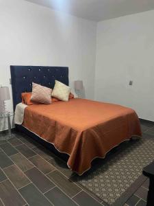 un letto con coperta arancione e cuscini sopra di DEPARTAMENTO DE 3 RECAMARAS RECIEN RENOVADO LISTO PARA TU ESTADIA . a Morelia