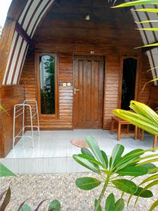 una veranda anteriore di una casa con porta in legno di Mirna Homestay a Gili Air