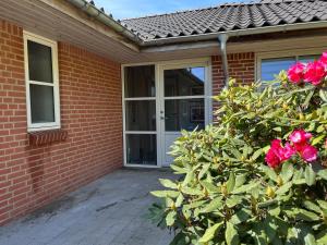 una casa de ladrillo con una puerta y un arbusto con rosas en Kørestolsvenligt dbl. vær., en Nykøbing Mors
