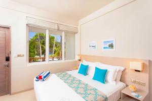 a bedroom with a bed with blue and white pillows at Malahini Kuda Bandos Resort in North Male Atoll