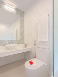 a white bathroom with a toilet and a sink at Malahini Kuda Bandos Resort in North Male Atoll