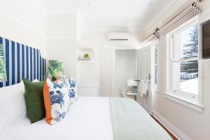 a white bedroom with a large bed and a window at Barrenjoey House in Palm Beach