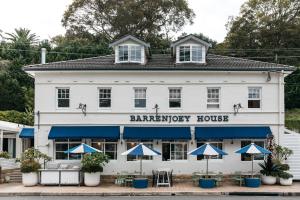 棕榈滩Barrenjoey House的前面有蓝色伞的白色建筑