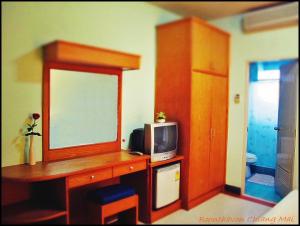 Habitación con escritorio, TV y espejo. en Boonthavon, en Chiang Mai