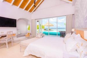 a bedroom with a bed and a view of the ocean at Malahini Kuda Bandos Resort in North Male Atoll