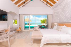 a bedroom with a bed and a view of the ocean at Malahini Kuda Bandos Resort in North Male Atoll