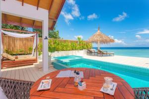 a villa with a swimming pool and the ocean at Malahini Kuda Bandos Resort in North Male Atoll