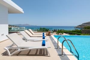 einen Pool mit Chaiselongues neben einem Pool in der Unterkunft Villa Milena with private pool, Vlicha beach Lindos in Lindos