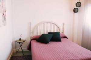 1 cama con edredón rosa y 2 almohadas en Casa Beta Ven A Disfrutarla, en Buenavista del Norte