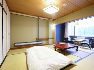 a room with a bed, chair, table and a lamp at Hotel Yudanaka in Yamanouchi