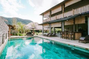 a swimming pool in front of a house at Baha Baha Villas West Sumbawa Yoyos Wellness Center, Gym, Yoga, Skate Park, Bar & Cafe in Sekongkang