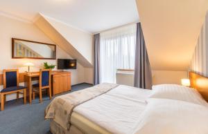 a hotel room with a large bed and a desk at Astra Dziwnówek Dom Gościnny in Dziwnówek