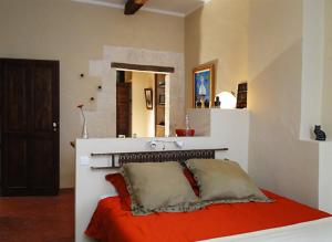 una camera da letto con un letto con lenzuola rosse e uno specchio di Tomettes ad Avignone
