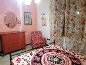 a bedroom with a bed and a chair and a mirror at Casa delle Rose Appartamento Gelsomino in San Mauro Pascoli