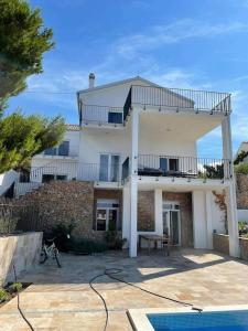 een groot wit huis met een balkon. bij Spacious new villa with pool above the pristine beach - FIRST SEASON PRICING!!! in Prvić Šepurine