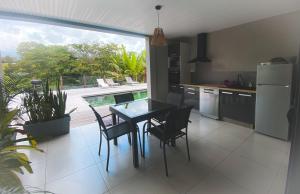 una cucina con tavolo e sedie e una grande finestra di KAZ'ANTILLAISE TI LUCA APPARTEMENT 3/4 PERS. a Le Lamentin