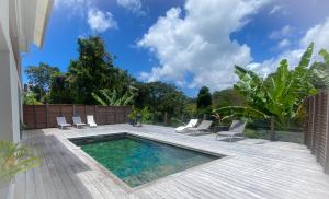 un cortile con piscina e sedie su un ponte di legno di KAZ'ANTILLAISE TI LUCA APPARTEMENT 3/4 PERS. a Le Lamentin