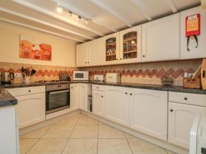 a large white kitchen with white cabinets and appliances at Mews Cottage in Minehead