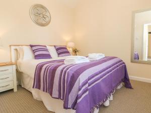 ein Schlafzimmer mit einem Bett mit einer lila Decke in der Unterkunft Mews Cottage in Minehead