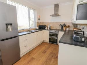 a kitchen with white cabinets and a stainless steel refrigerator at The Nook in Benllech