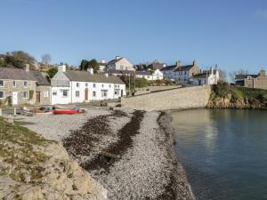 a rocky shore with houses and a body of water at The Nook in Benllech