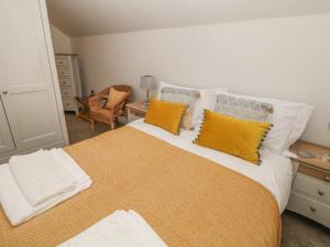 une chambre avec un grand lit avec des oreillers jaunes dans l'établissement Willow Cottage, à Sheffield