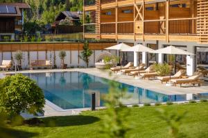 a hotel with a swimming pool with chairs and umbrellas at Natur Resort RISSBACHER in Stumm