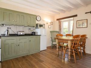 uma cozinha com armários verdes e uma mesa de madeira em Little Trespettigue em Launceston