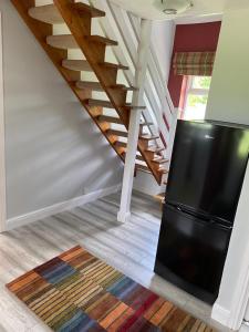 a living room with a black refrigerator and stairs at Beck Hill Cottage In Brandsby in York