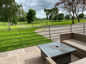 a patio with a table and a fence and grass at Beck Hill Cottage In Brandsby in York