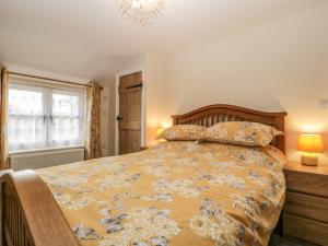 a bedroom with a bed and a window and a chandelier at Cosynook Cottage in Blandford Forum