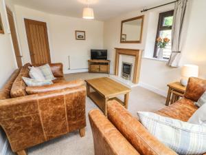 a living room with leather furniture and a tv at The Coach House in Carnforth