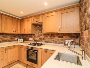 a kitchen with wooden cabinets and a sink at The Coach House in Carnforth