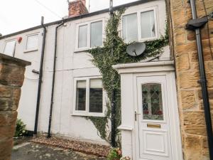 an ivy covered house with a white door at Swainby Cottage in Northallerton