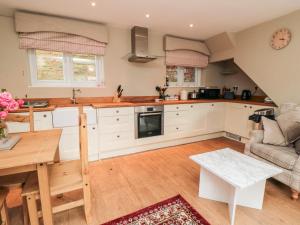 une cuisine avec des placards blancs et une table dans l'établissement Swainby Cottage, à Northallerton