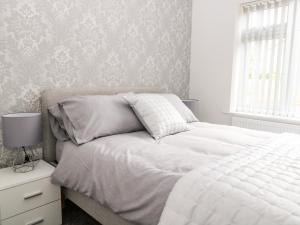 a bedroom with a white bed and a window at Harbour Place in Wells next the Sea