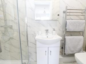 a white bathroom with a sink and a shower at Harbour Place in Wells next the Sea +14 photos