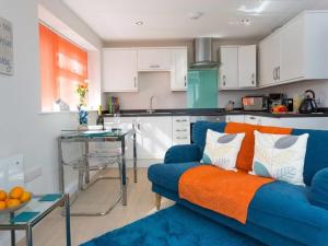 Una sala de estar con un sofá azul y una cocina. en Egret, en Brixham 16 fotos más
