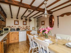 une cuisine avec une table en bois ornée de fleurs roses dans l'établissement Daisy Cottage, à Penrith