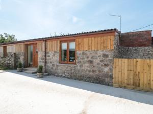 a stone and wood building with a stone wall at The Old Cow Shed in Banwell