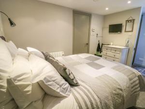 1 dormitorio con 1 cama con almohadas blancas y TV en Dibble Cottage, en Richmond