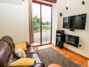 a living room with a leather couch and a flat screen tv at The Barn at Heath Hall Farm in Sowerby Bridge