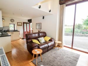 uma sala de estar com um sofá de couro castanho e uma cozinha em The Barn at Heath Hall Farm em Sowerby Bridge