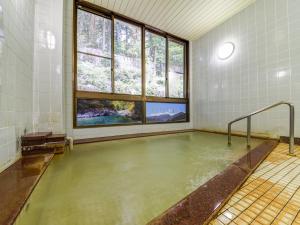 ein großer Pool mit Wasser in einem Zimmer mit Fenstern in der Unterkunft 阿寺温泉 フォレスパ木曽あてら荘 in Okuwa