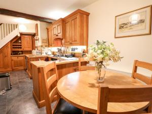 una cocina con una mesa de madera con un jarrón de flores. en Woodbine Cottage en Matlock