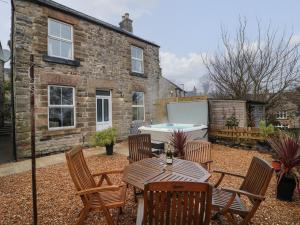 a patio with a table and chairs and a bath tub at Woodbine Cottage in Matlock