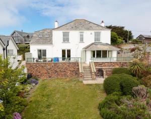 a large white house with a brick wall at Worthy House in Polzeath