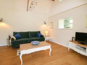 a living room with a green couch and a coffee table at Wheelwrights Cottage in Grantham